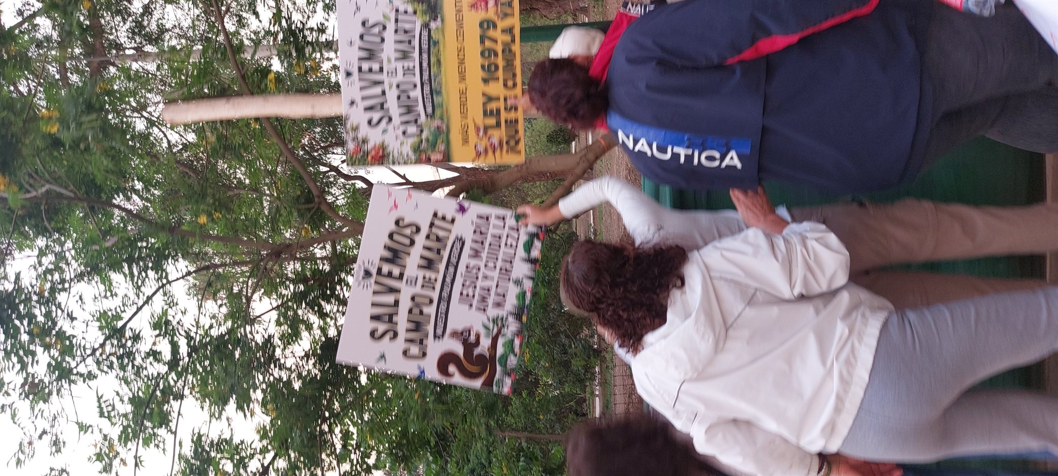 Vecinos con carteles de «Salvemos el Campo de Marte» y «Ley 16979, ¡que se cumpla ya!» junto a los árboles del parque